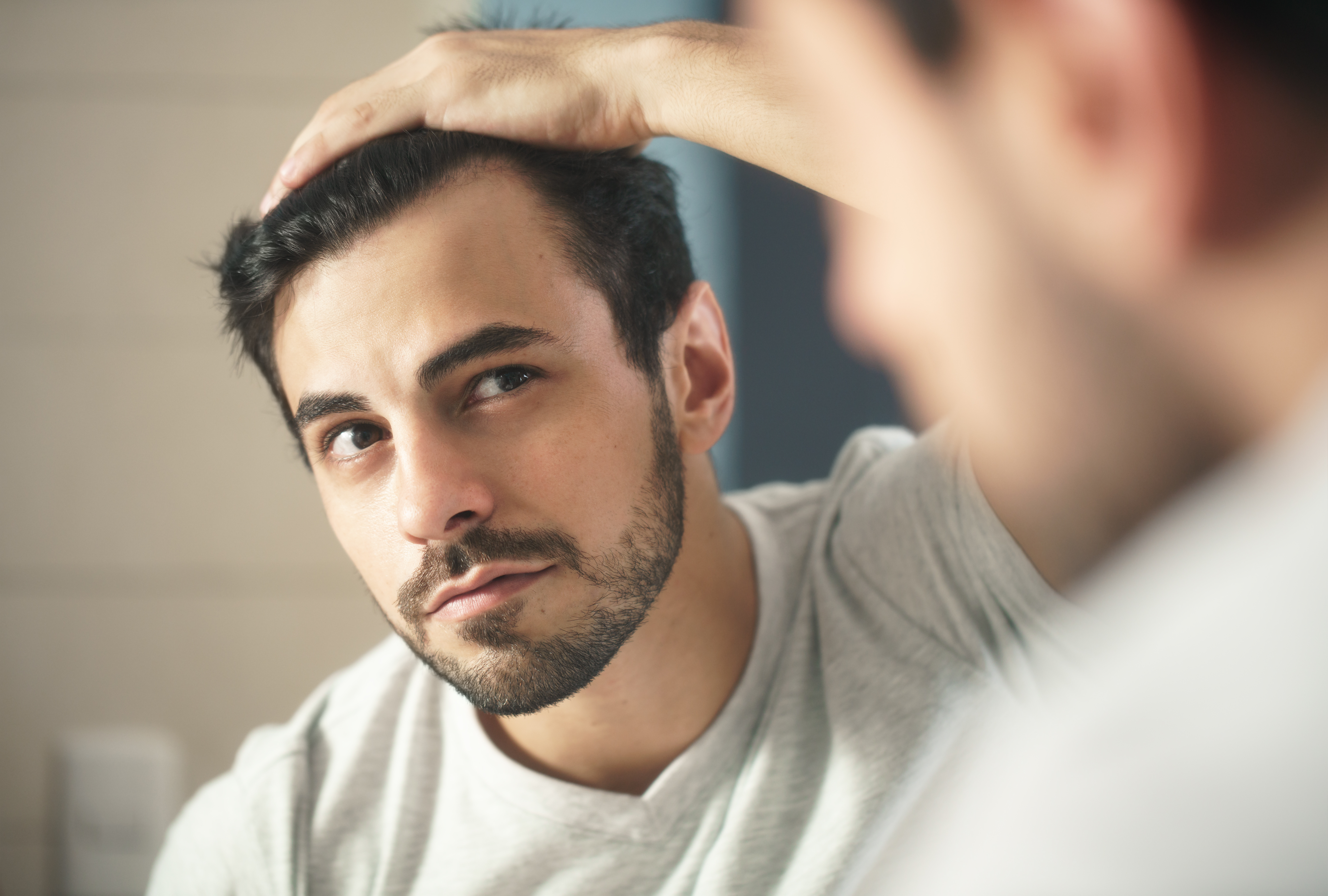 Mann betrachtet sein Haar im Spiegel